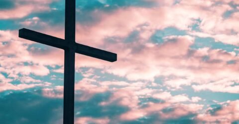 A cross in front of a pink sunset